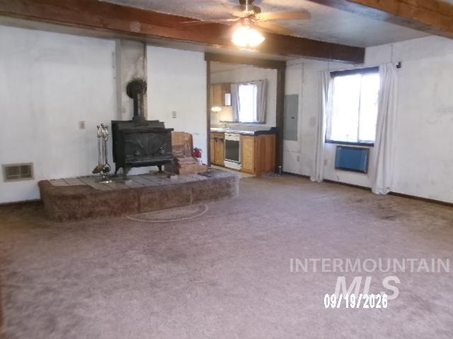 31997 2nd Fork Road Ola, ID 83657 - Photo 10 of 47 Exposed ceiling beams, wood-burning stove with a tiled hearth, ceiling fan, and built-in kitchen cabinetry with a countertop