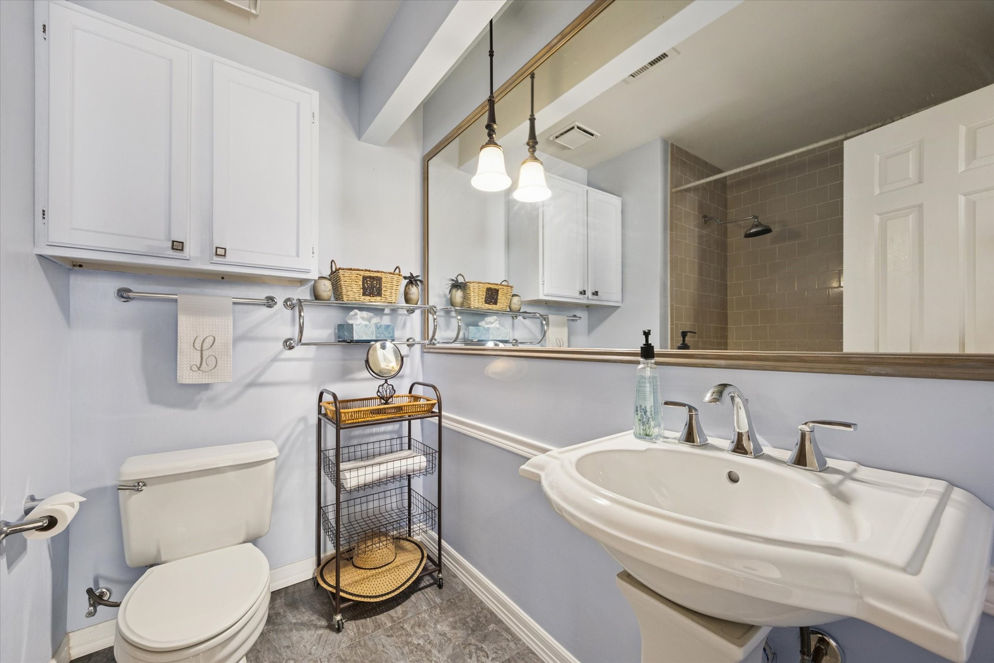 926 Rutland Street Houston, TX 77008 - Photo 12 of 28 The primary bath features a pedestal sink, dedicated cabinet storage, and a tub/shower combo. Timeless tile work completes the space, offering a clean and durable finish.