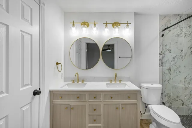 a bathroom with a toilet sink vanity and mirror
