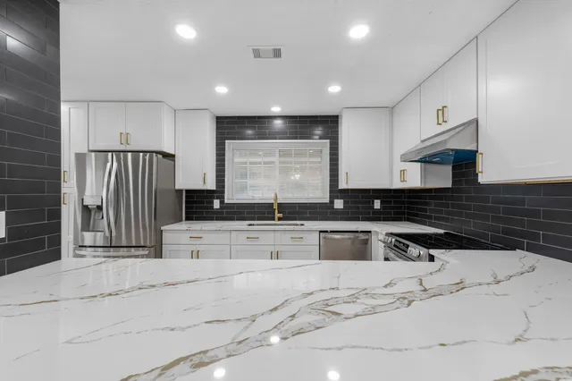 a kitchen with stainless steel appliances kitchen island granite countertop a stove a sink and a refrigerator