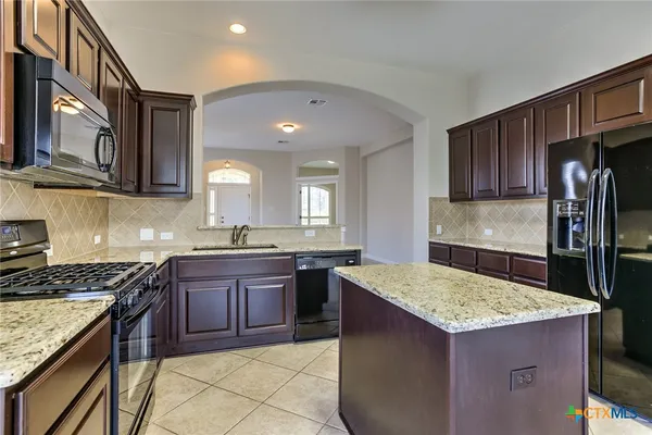 a kitchen with stainless steel appliances granite countertop a refrigerator a stove and a sink