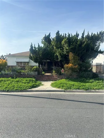 a front view of a house with a yard and potted plants