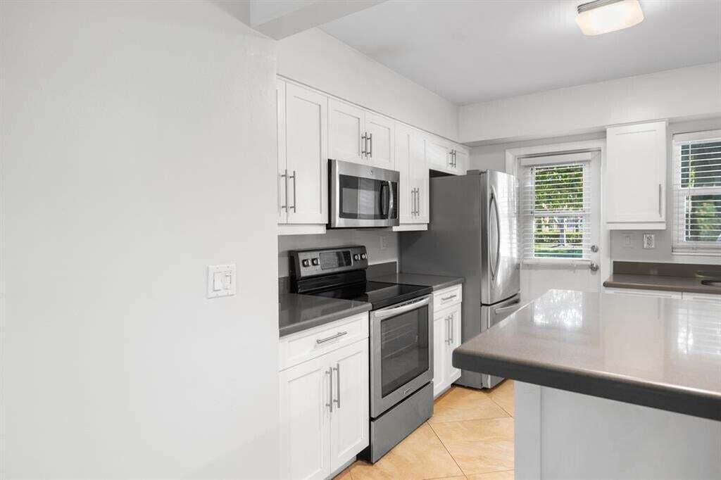 3801 Northeast 22nd Terrace, Unit 2 Lighthouse Point, FL 33064 - Photo 2 of 19 a kitchen with granite countertop a stove a sink a microwave a refrigerator and cabinets
