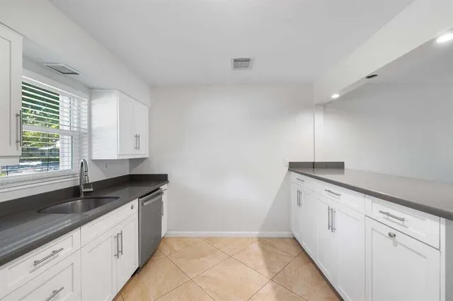 a kitchen with granite countertop white cabinets and window
