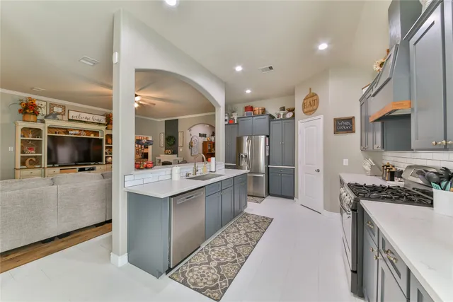 a large white kitchen with a large counter top and stainless steel appliances