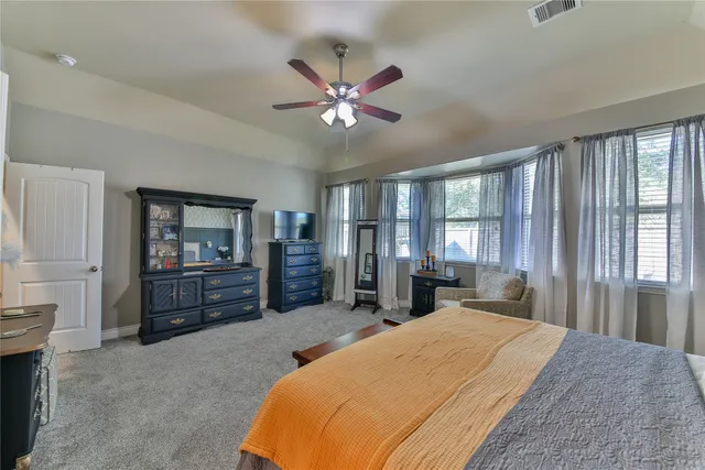 a bedroom with a bed dresser and a large window