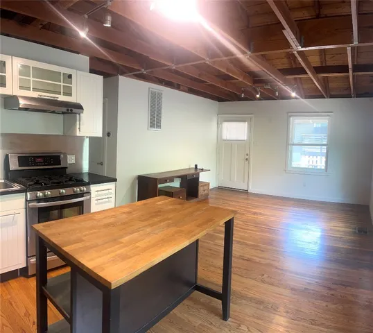 a kitchen with stainless steel appliances granite countertop a stove a refrigerator a sink dishwasher with a dining table and chairs with wooden floor