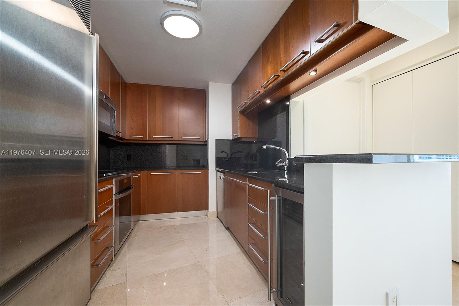 901 Brickell Key Boulevard, Unit 901 Miami, FL 33131 - Photo 20 of 35 a kitchen with granite countertop a refrigerator and microwave