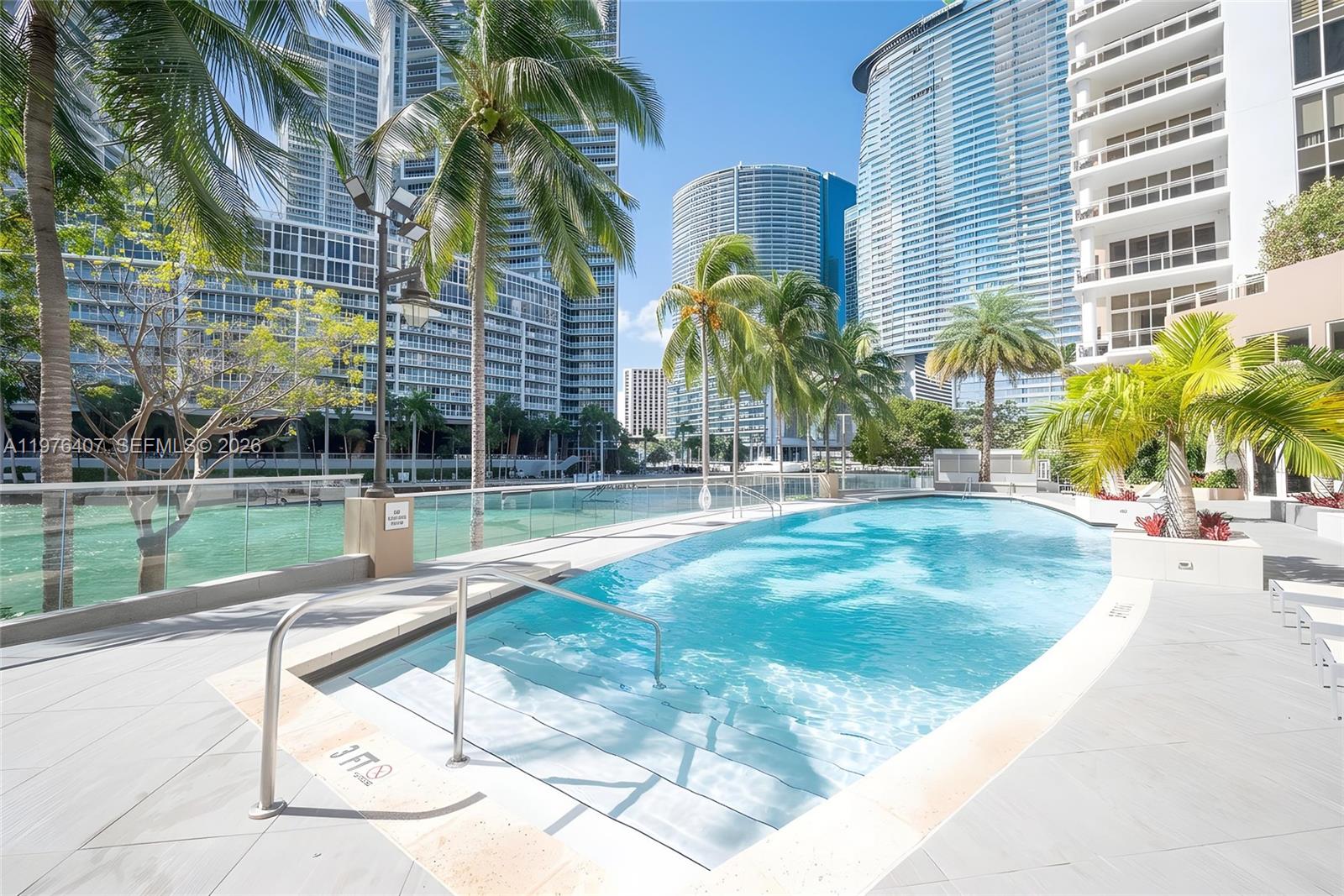 901 Brickell Key Boulevard, Unit 901 Miami, FL 33131 - Photo 27 of 35 a view of a swimming pool with a bench and trees in the background
