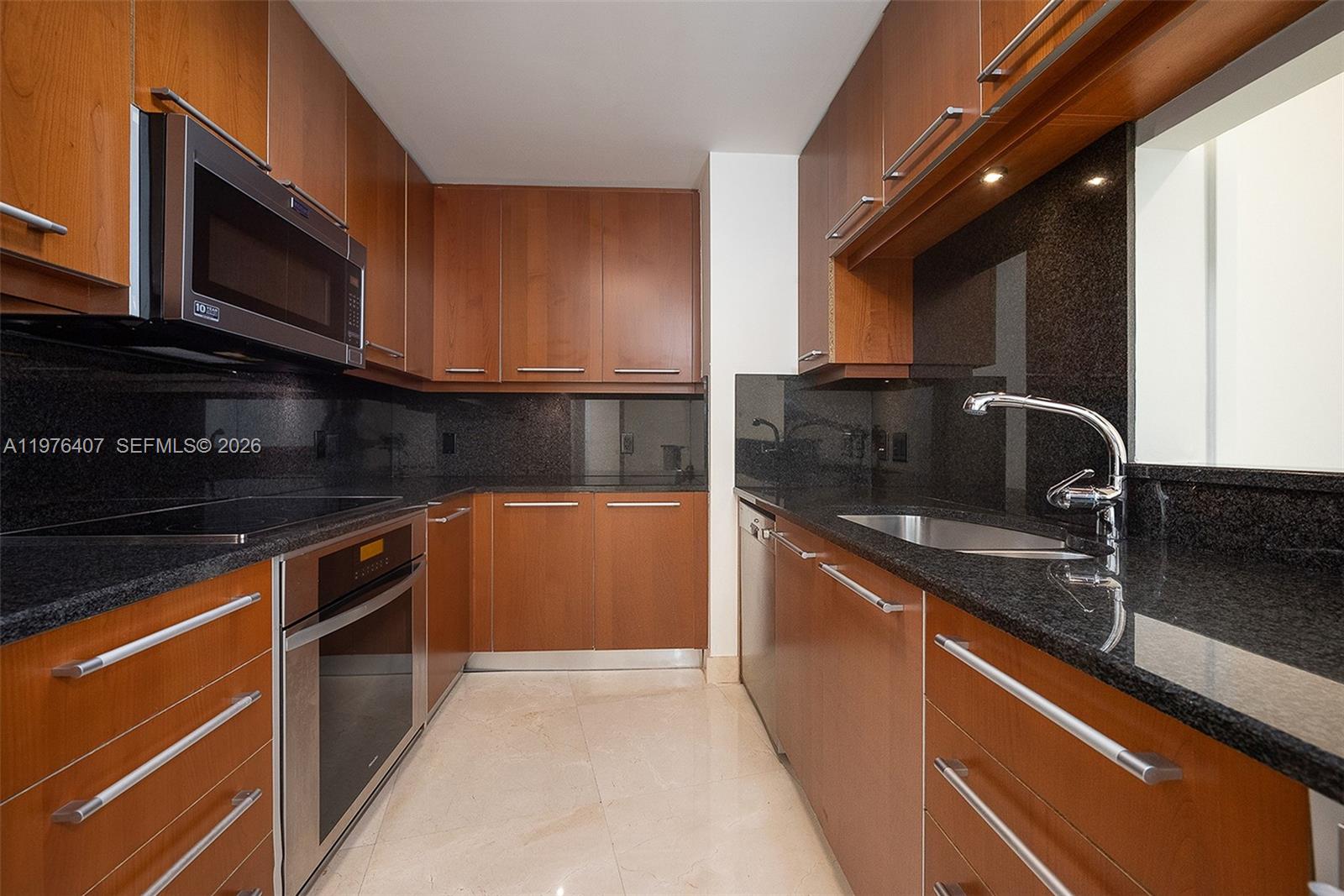 901 Brickell Key Boulevard, Unit 901 Miami, FL 33131 - Photo 6 of 35 a kitchen with stainless steel appliances granite countertop a sink stove and microwave