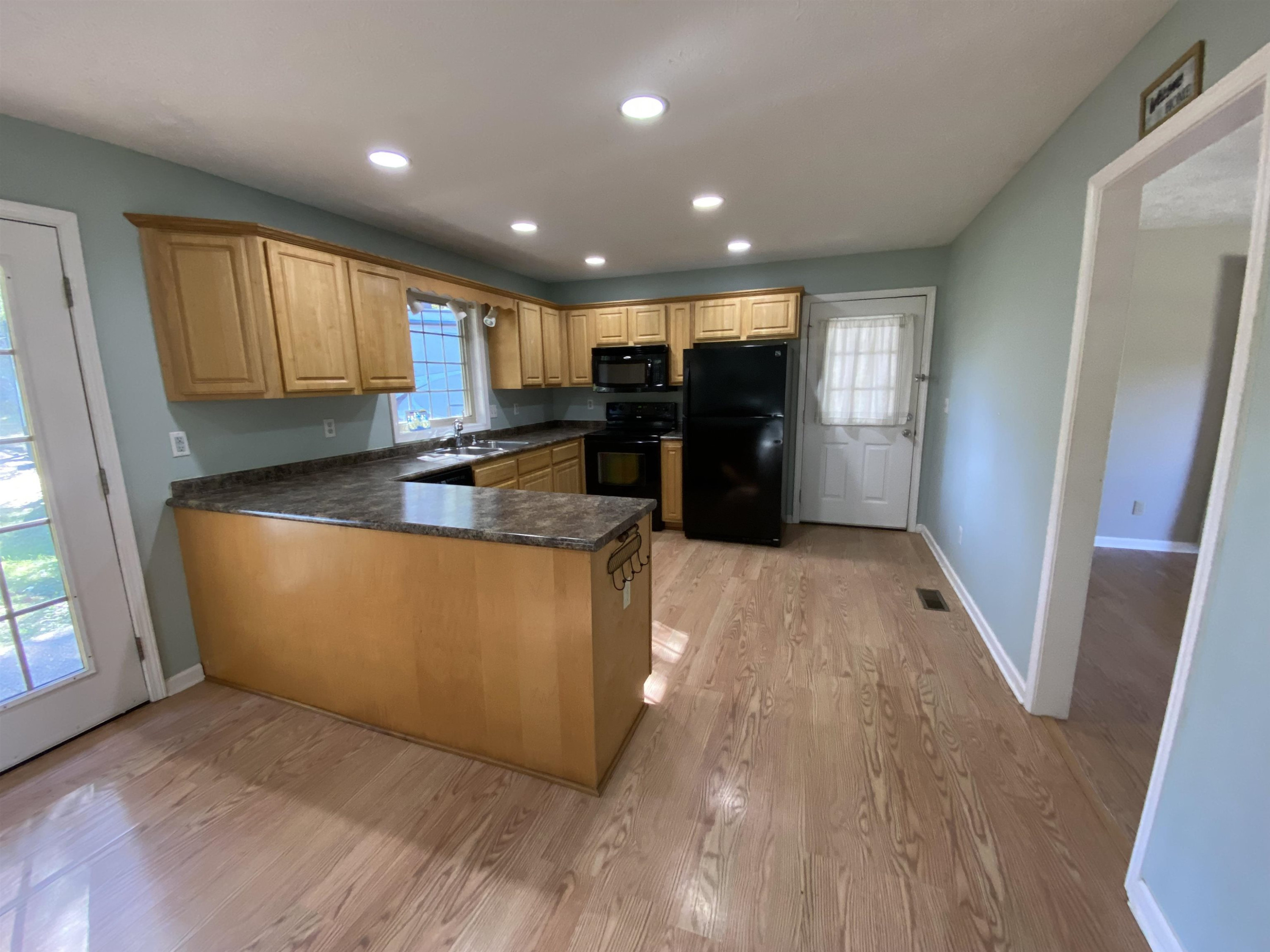 610 Old Finger Road Henderson, TN 38340 - Photo 19 of 24 a kitchen with stainless steel appliances granite countertop a refrigerator a sink a stove a microwave a sink and white cabinets with wooden floor
