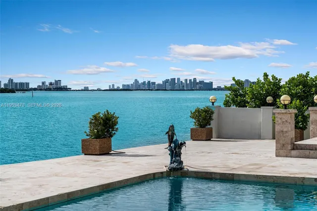 a view of a patio with couches table and chairs under an umbrella with large trees