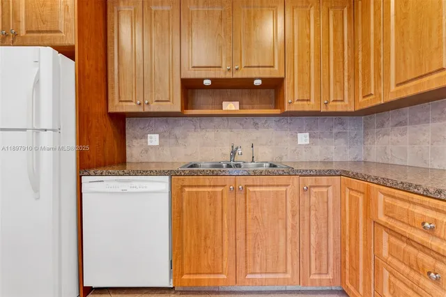 a kitchen with stainless steel appliances granite countertop white cabinets a refrigerator and a sink