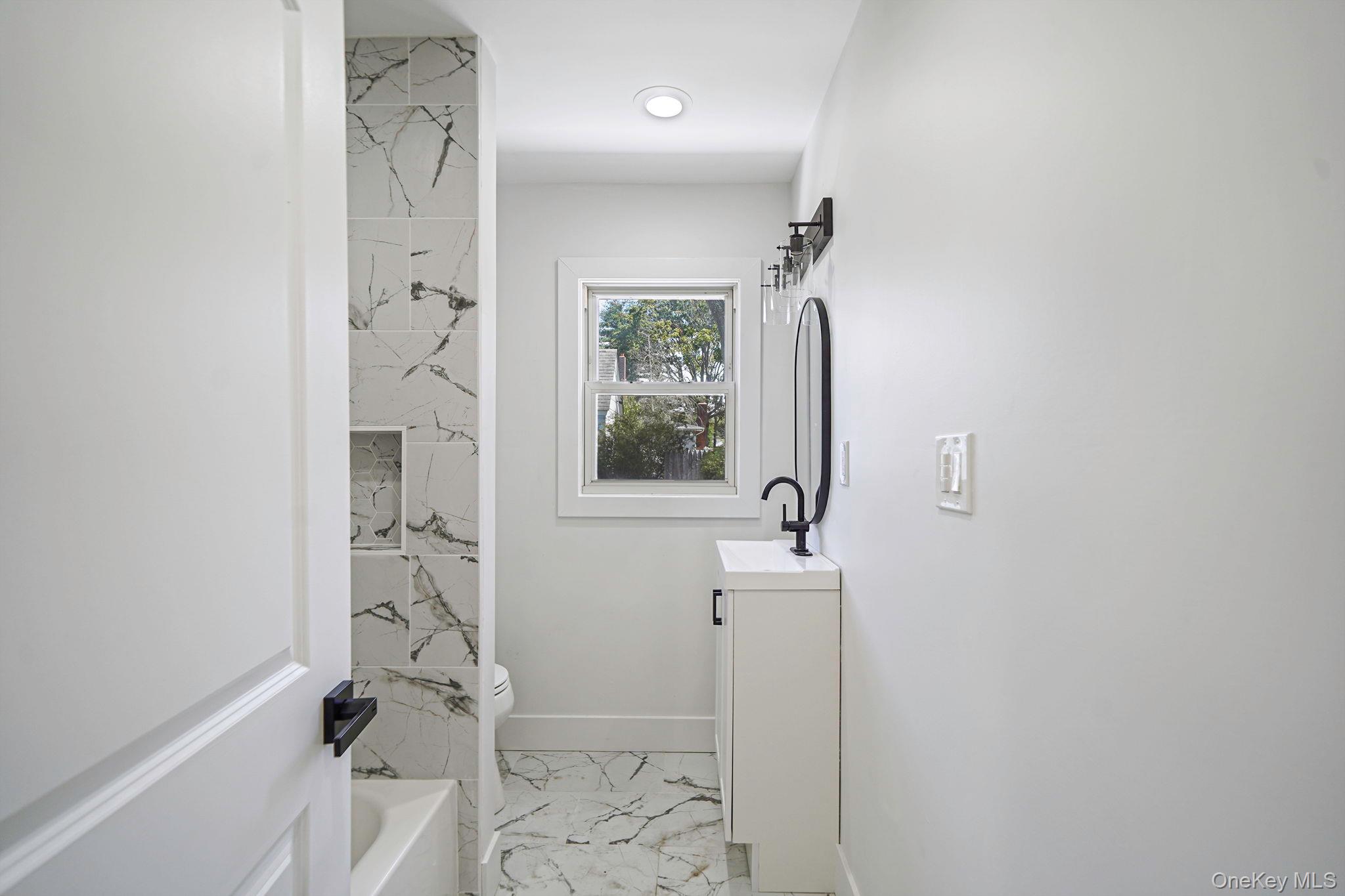 48 Vernon Street Patchogue, NY 11772 - Photo 13 of 31 Bathroom with vanity, light marble finish floors, and shower / tub combination
