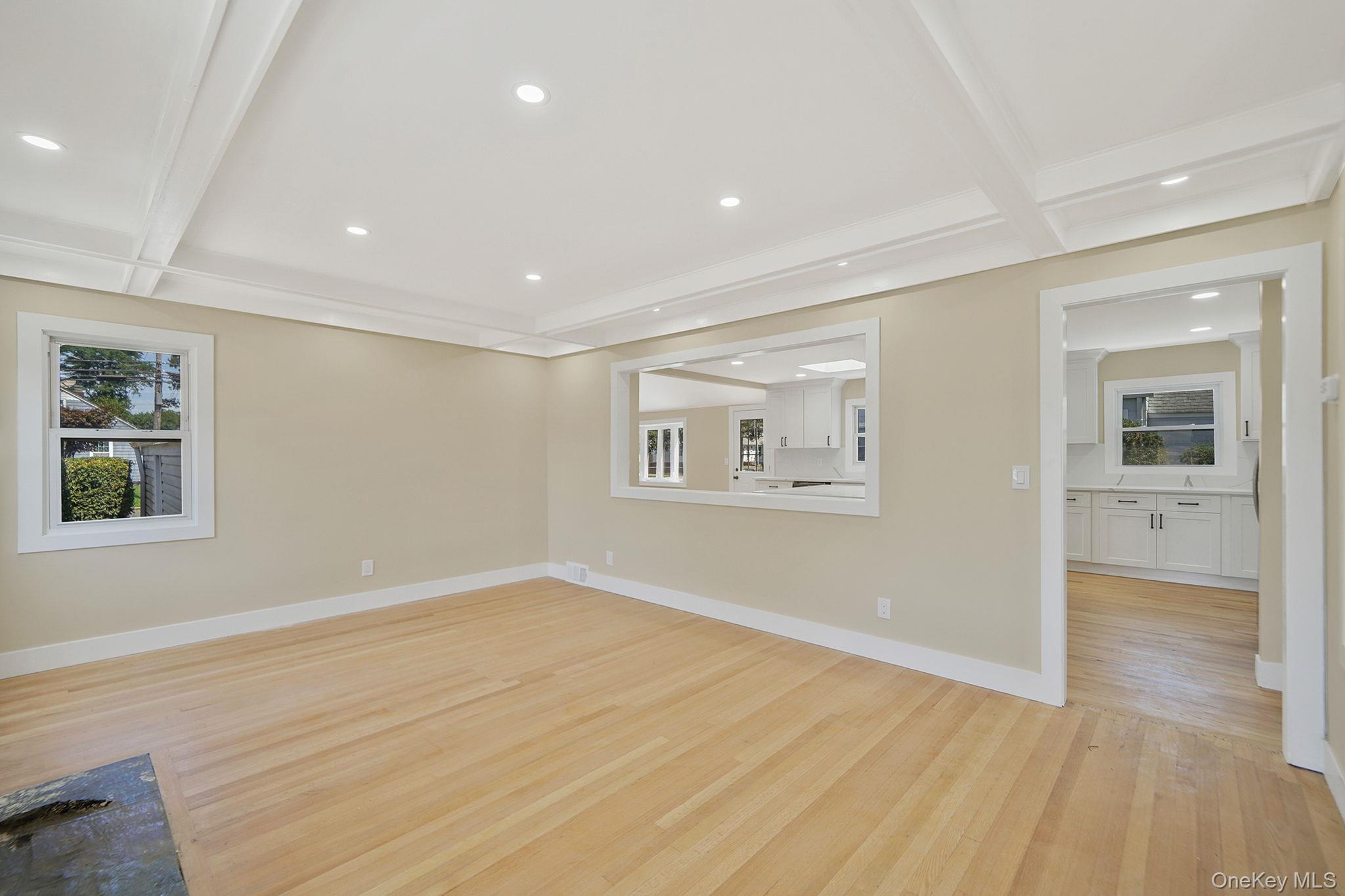 48 Vernon Street Patchogue, NY 11772 - Photo 3 of 31 Unfurnished living room featuring beamed ceiling, healthy amount of natural light, recessed lighting, coffered ceiling, and light wood-style floors