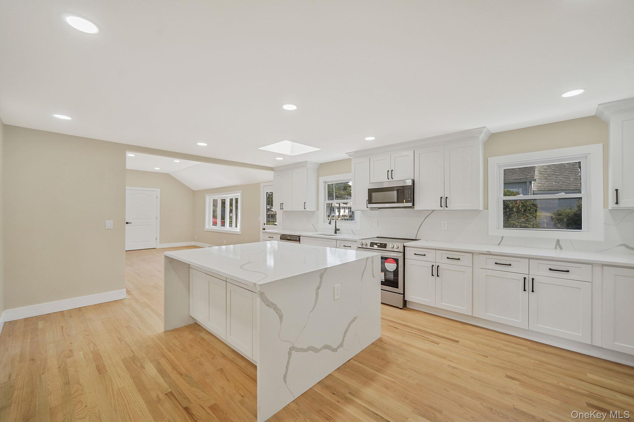 48 Vernon Street Patchogue, NY 11772 - Photo 5 of 31 Kitchen with a kitchen island, a skylight, stainless steel appliances, white cabinets, and recessed lighting