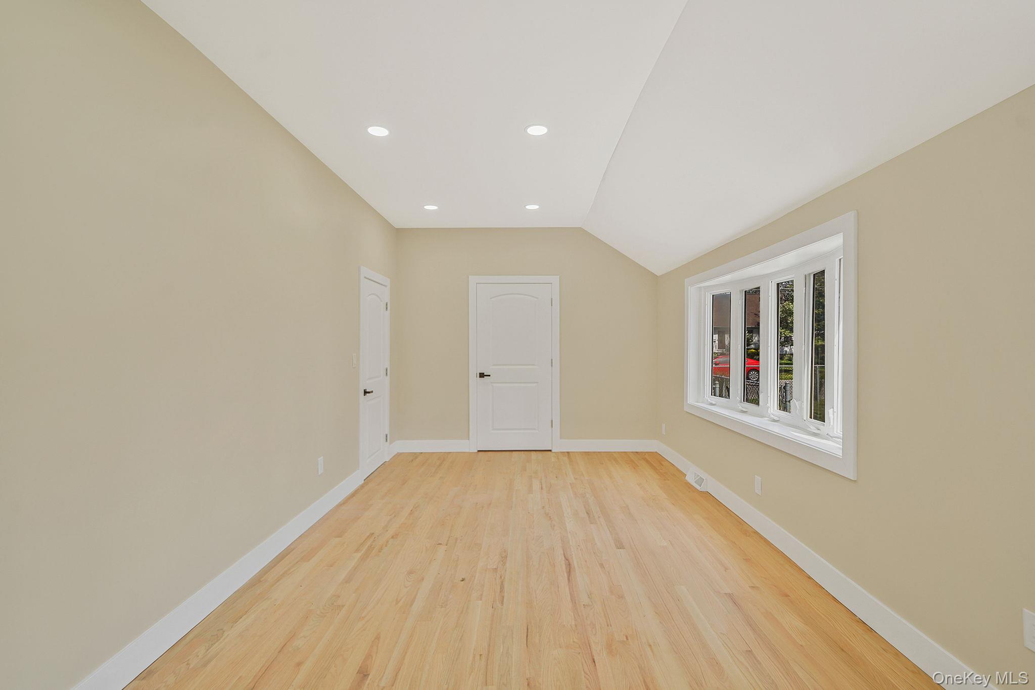 48 Vernon Street Patchogue, NY 11772 - Photo 9 of 31 Unfurnished room with vaulted ceiling, recessed lighting, and light wood-style floors