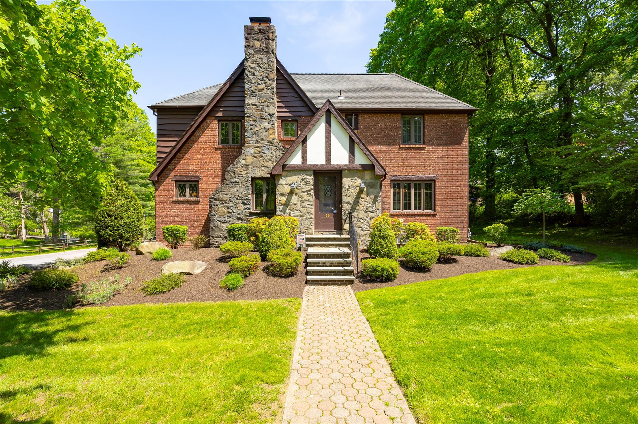 Tudor home with a front lawn, a chimney, stone siding, and roof with shingles
