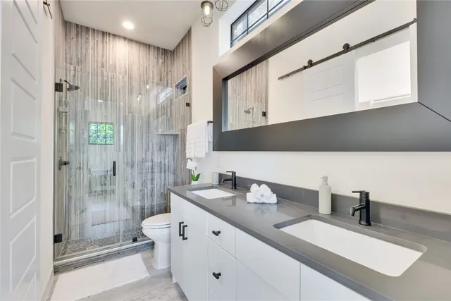 a bathroom with a double vanity sink mirror and shower