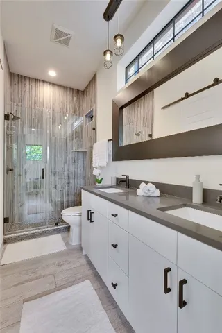a spacious bathroom with double vanity a mirror and a shower