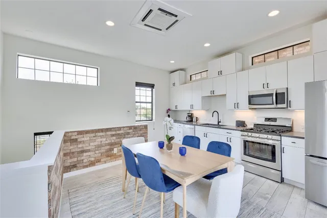 a white kitchen with a stove a sink a dining table and chairs