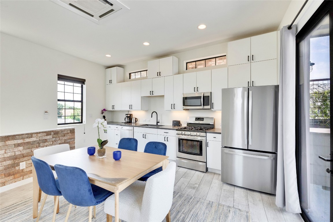 808 Lydia Street Austin, TX 78702 - Photo 19 of 40 a kitchen with stainless steel appliances a stove a sink dishwasher a refrigerator white cabinets and wooden floor