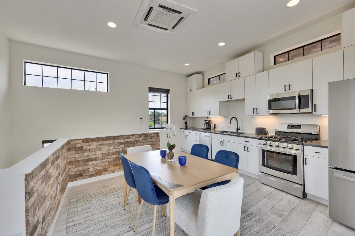 808 Lydia Street Austin, TX 78702 - Photo 27 of 40 a kitchen with stainless steel appliances granite countertop a stove a sink dishwasher a refrigerator white cabinets and wooden floor next to a window