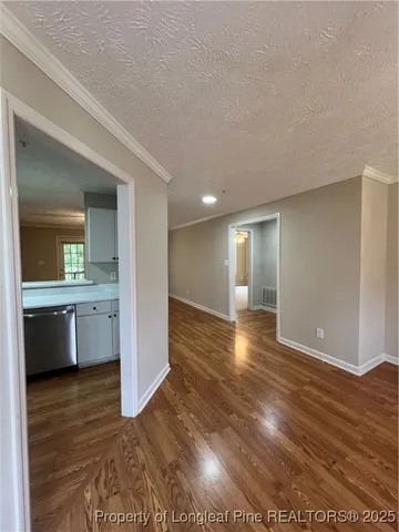 a view of a kitchen and an empty room with wooden floor and kitchen view