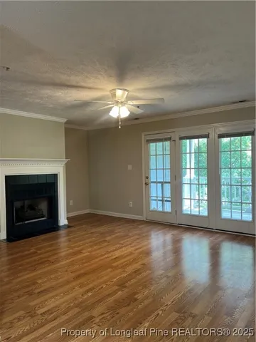 a view of an empty room with wooden floor fireplace and a window