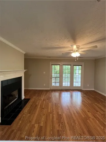 a view of an empty room with wooden floor fireplace and a window
