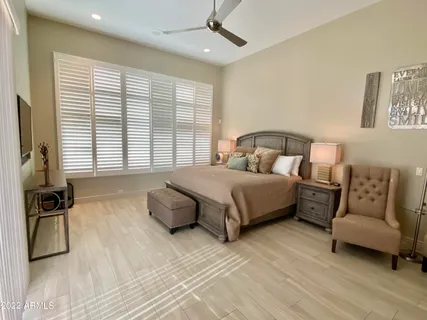 a bedroom with a bed a couch and a flat tv screen on dresser