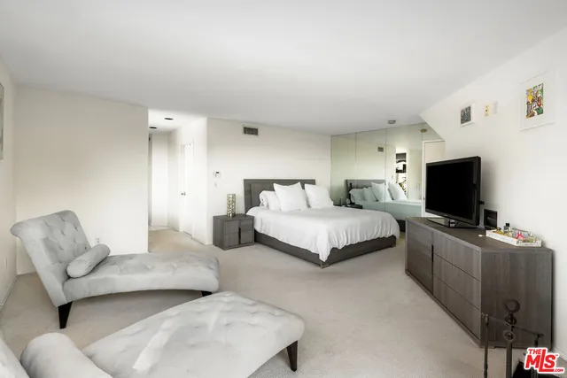 a spacious bedroom with a bed and a flat screen television