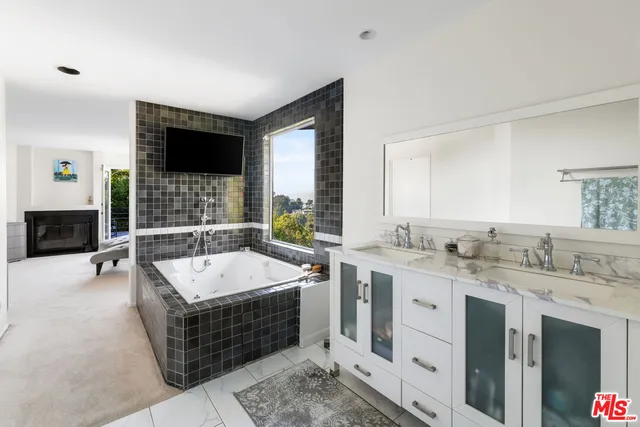 a spacious bathroom with a tub a double vanity sink and a large mirror