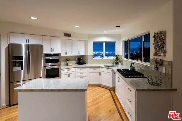 a kitchen with stainless steel appliances granite countertop a stove top oven a sink and dishwasher a refrigerator with wooden floor