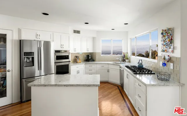 a kitchen with stainless steel appliances a sink stove refrigerator and cabinets