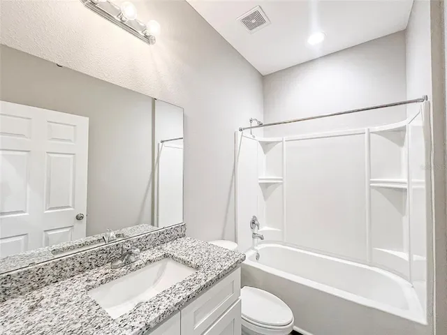 a bathroom with a granite countertop sink a mirror and a shower