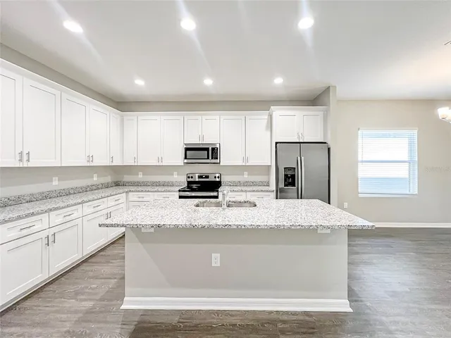 a kitchen with stainless steel appliances granite countertop a sink a stove a refrigerator cabinets and a center island