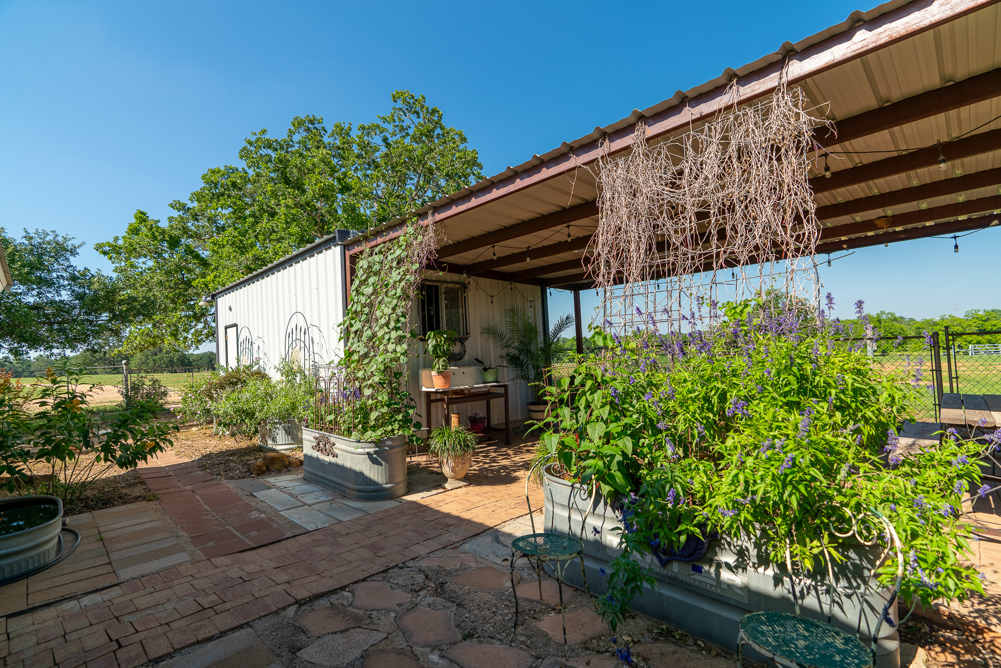 400 619th Spur Elgin, TX 78621 - Photo 30 of 40 A charming rustic outbuilding with a shaded patio and abundant potted greenery.