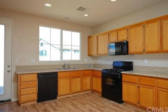 a kitchen with stainless steel appliances granite countertop wooden cabinets a stove a sink and a window