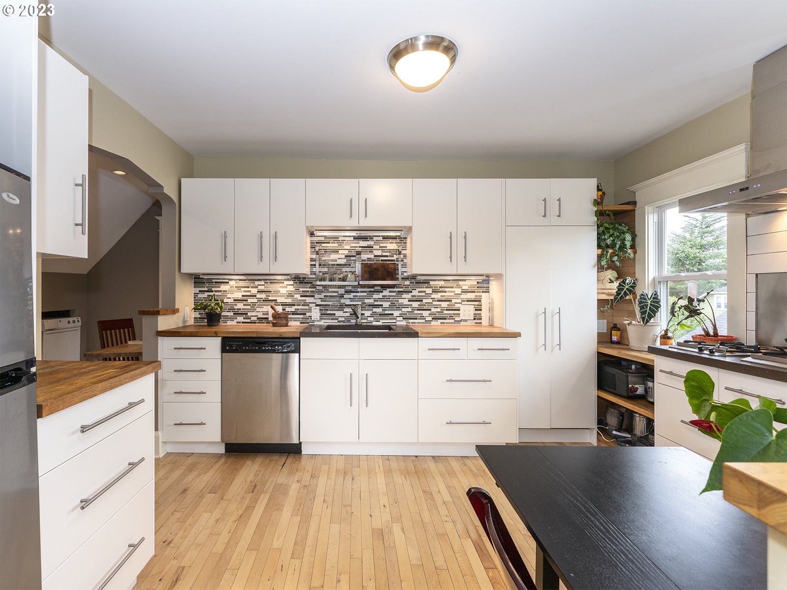 314 Northeast 69th Avenue Portland, OR 97213 - Photo 22 of 37 a kitchen with granite countertop a stove top oven a sink a dining table and chairs with wooden floor