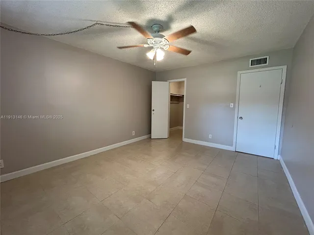 an empty room with closet and ceiling fan