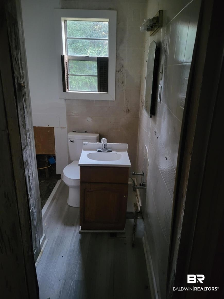 2059 Magnolia Lane Mobile, AL 36605 - Photo 6 of 17 Bathroom with toilet, wood finished floors, vanity, and tile walls
