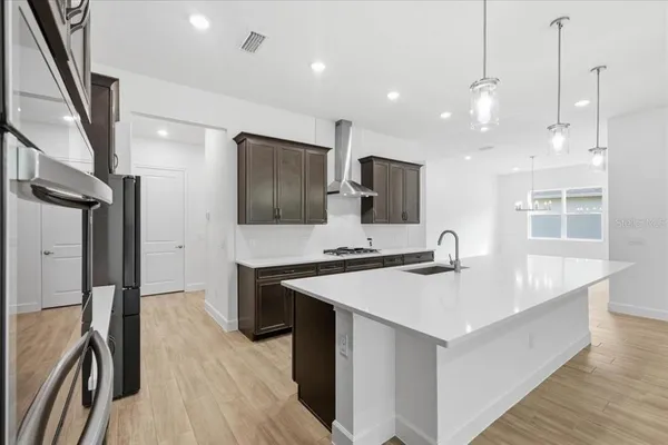 a large kitchen with a large counter top a sink stainless steel appliances and cabinets