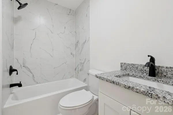 a bathroom with a granite countertop sink toilet and bathtub
