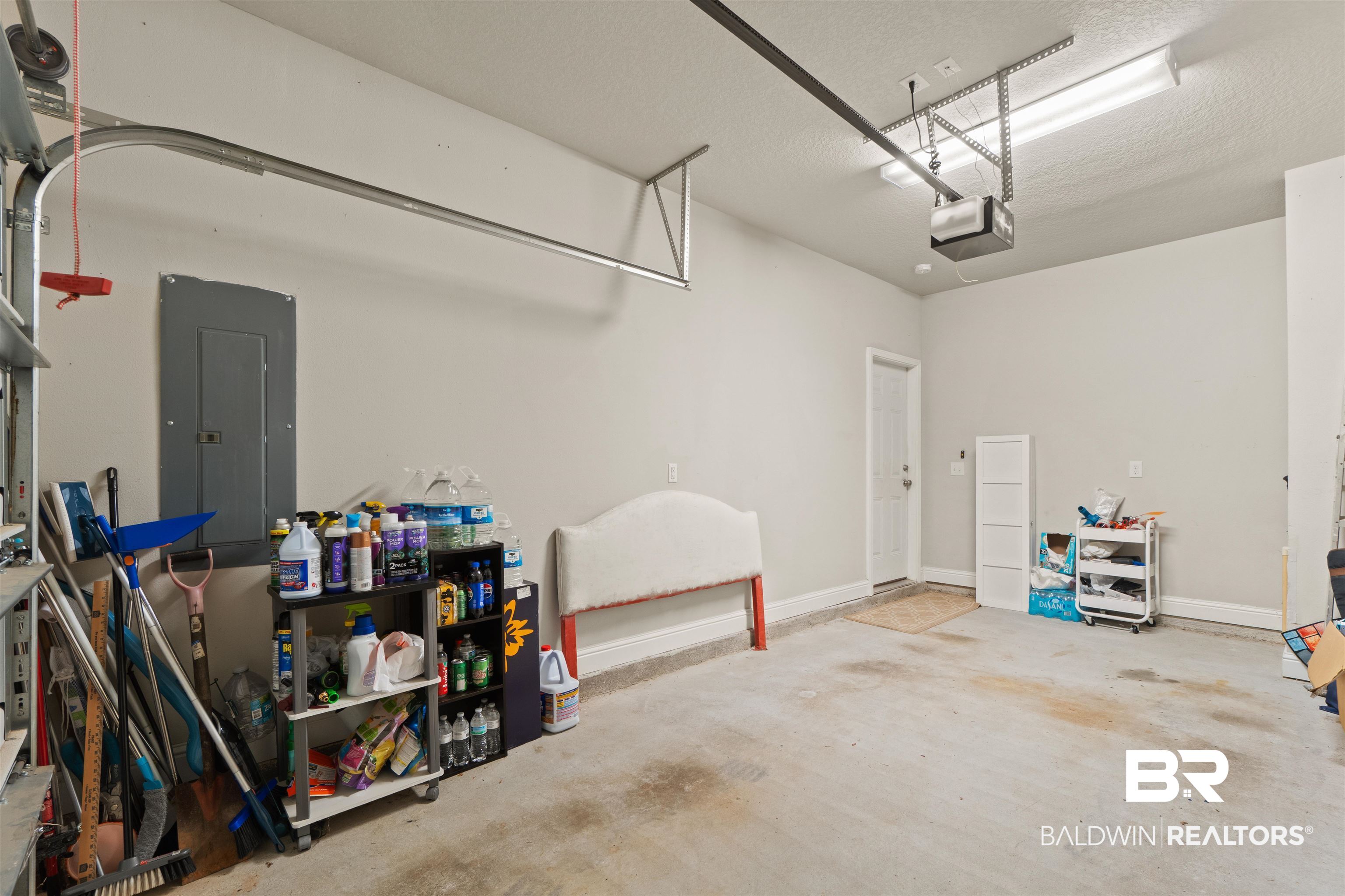 25806 Pollard Road, Unit 6 Daphne, AL 36526 - Photo 10 of 38 Spacious garage featuring a durable concrete floor, overhead lighting, an electric garage door opener, and a wall-mounted electrical panel