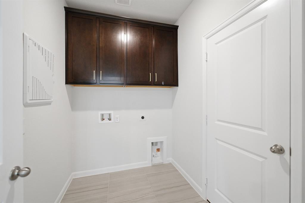 1908 Sangallo Lane Celina, TX 75009 - Photo 32 of 35 Dedicated utility space featuring ample wall cabinetry, light-toned flooring, white baseboards, and a paneled interior door