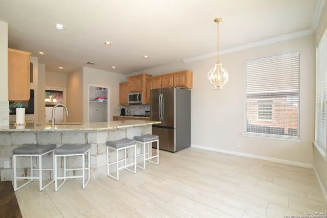 a kitchen with stainless steel appliances kitchen island granite countertop a refrigerator a stove top oven and a dining table with wooden floor