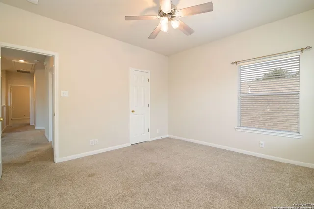 an empty room with a window and a fan