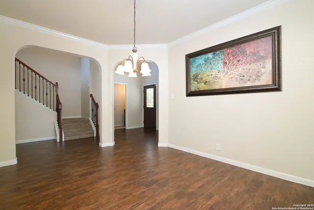 a view of a hallway with wooden floor and chandelier