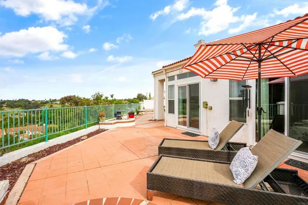 a view of a patio with couches table and chairs under an umbrella
